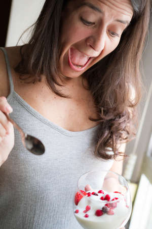 Attractive middle-aged brunette Spanish woman posing with a glass of ice cream with fruitsの写真素材