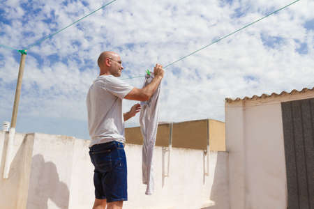 Spanish housekeeper laying the laundry on the roof of a houseの写真素材