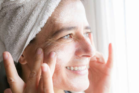 Face and body care with creams. Happy middle-aged womanの写真素材