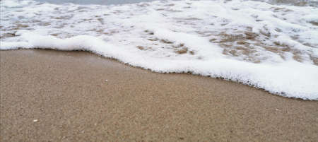 Detail of small waves arriving at the shore of the beach. relaxation and peace