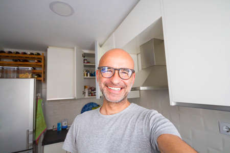 Cheerful bald man householder enjoying the kitchenの写真素材