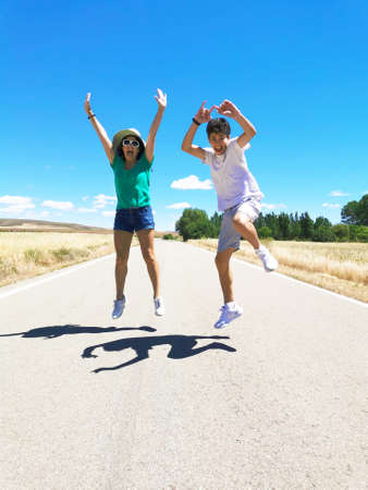 Happy family celebrating, running, jumping and playing along a lonely road.の写真素材