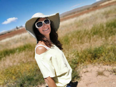Attractive middle-aged happy woman in a hat enjoying the countryside and holidaysの写真素材