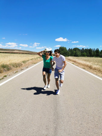 Happy family celebrating, running, jumping and playing along a lonely road.の写真素材
