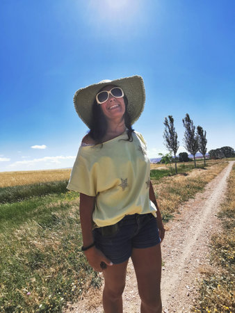 Attractive middle-aged happy woman in a hat enjoying the countryside and holidaysの写真素材