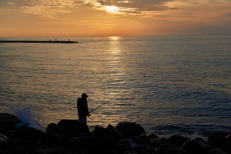 A silhouette of a fisherman on the beach in front of a spectacular sunriseの写真素材