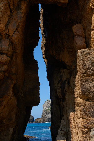 A large gap in some cliffs where you can see the sea on the other side.の写真素材
