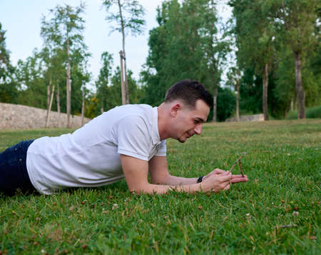 An attractive young man sitting on the grass in a park.の写真素材