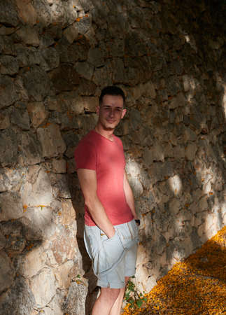 An attractive young man posing on a stone wall.の写真素材