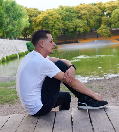 A young, attractive boy sitting by a riverの写真素材