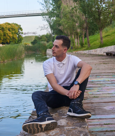 A young, attractive boy sitting by a riverの写真素材