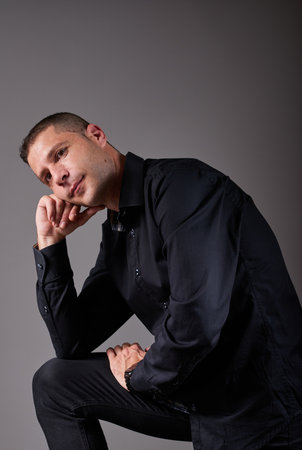 An attractive young man sitting in a chair in a pensive attitude.の写真素材