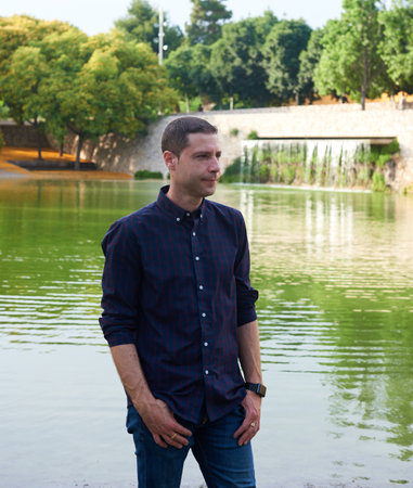 A young man in jeans posing at ease in a park.の写真素材