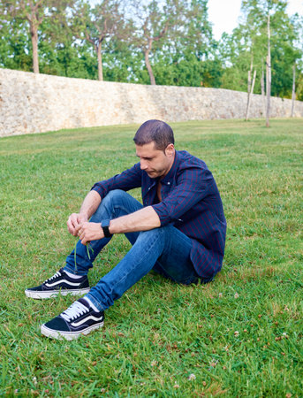 A young man posing relaxed on the grass in a park.の写真素材