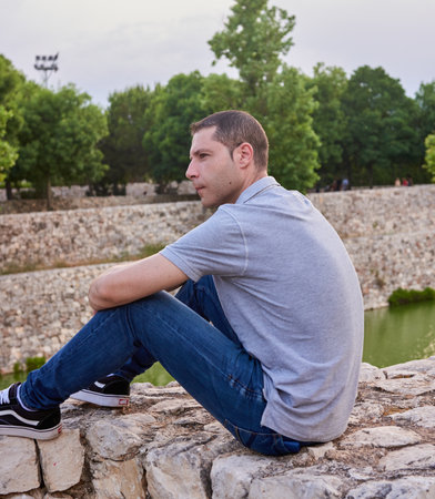 A young model seated on a wall in a parkの写真素材