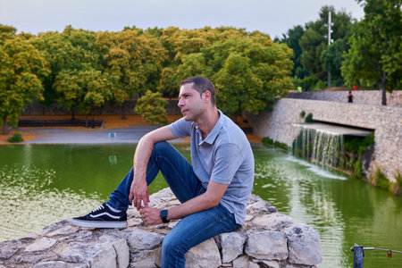A young model seated on a wall in a park