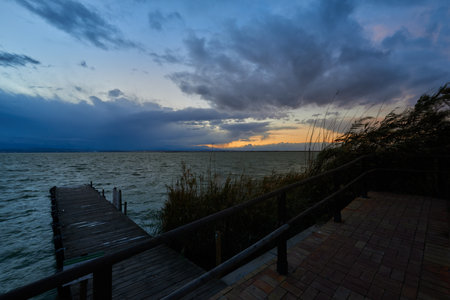 A beautiful sunset over a pier with a sky full of clouds.の写真素材