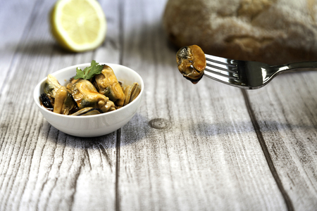 pickled mussels bow,  lemon slice, fork and bread on woodの写真素材