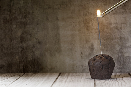 chocolate cupcake with flame on wood table with dark backgroundの写真素材