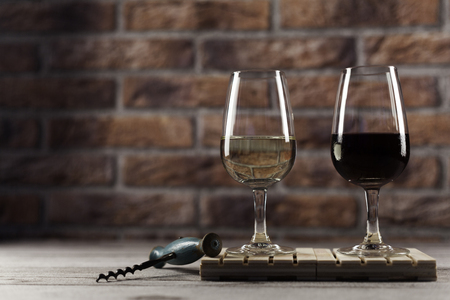 white and red wine glass on mini pallet with corkscrew on wood table and bricks backgroundの写真素材