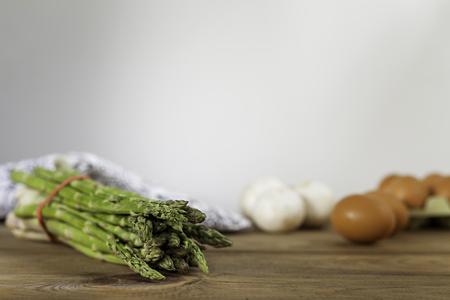 raw green asparagus, eggs and mushrooms on wood table and white backgroundの写真素材