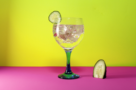 gin tonic with cucumber slice and cucumber segment  on pink and yellow backgroundの写真素材