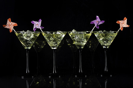 Four yellow cocktails garnished on black backgroundの写真素材