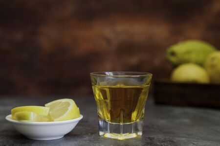 tequila shot with lemon slice and lemon basquet on brown fantasy background
