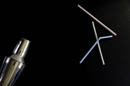Cocktail shaker and three straws on black background  from above. Copy space. Conceptの写真素材