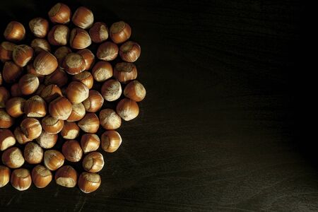 Handful of hazelnuts on black background top view. Copy space