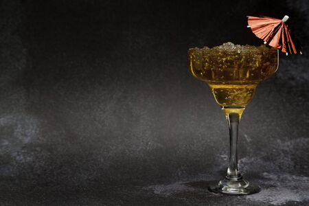 Iced tea cocktail glass with umbrella on dark background with copy spaceの写真素材