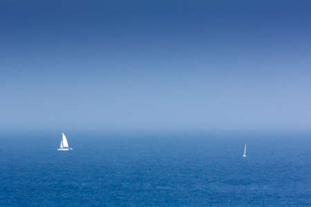 A sailboat and a catamaran sailing at the mouth of the Tagus River on the coast of Cascais. Portugalの写真素材