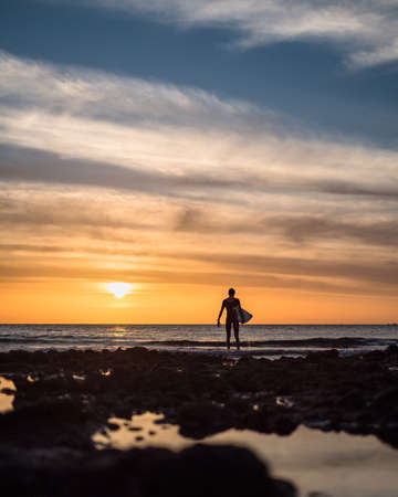 Silhouette of surfer at sunsetの写真素材