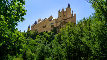 Medieval Castle on top of the mountain with green vegetation and blue sky. Alcazar Segovia Spain.のeditorial素材