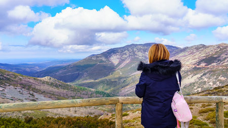 Woman contemplating the mountainous landscape from a viewpoint at the top of the hills.の写真素材