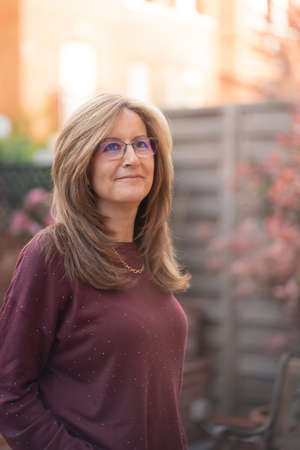 Mature white woman smiling in a happy attitude in the garden of her house.の写真素材