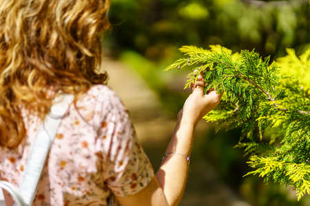 Woman taking a plant with her hand and observing its beauty.