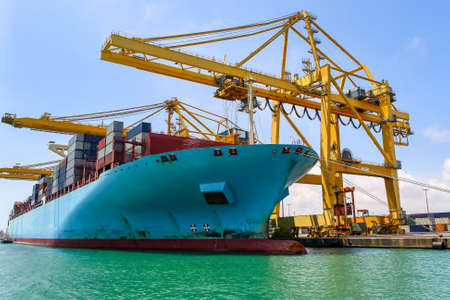 Large container cargo ship next to the cranes in the process of loading and unloading goods....