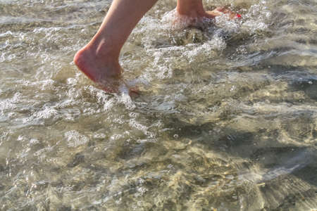 Wet woman feet walking on the beach stepping on the sand.の写真素材