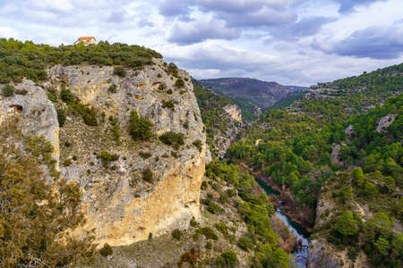 Rock canyon in the forest with a small house on top of the cliff.の写真素材