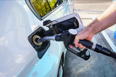 Hand of a man filling the fuel tank of the car at a gas station.