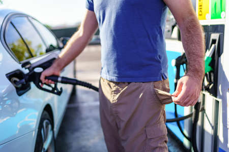 Man with empty pockets in sign of high fuel prices at gas stations.