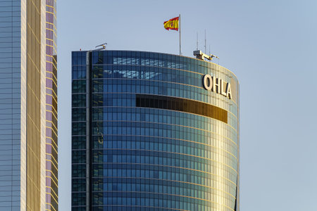 Madrid, Spain - July 30, 2022: Modern glass building headquarters of the multinational OHLA in the city of Madrid.のeditorial素材