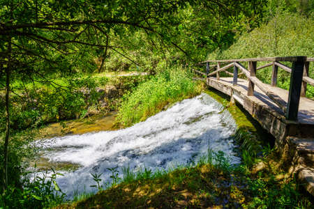 Small waterfall under a wooden bridge at the source of the Ebro river. Fontibre Cantabria.の写真素材