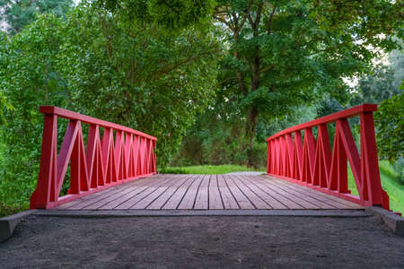 Wooden bridge over river in a public park full of greenery.の写真素材