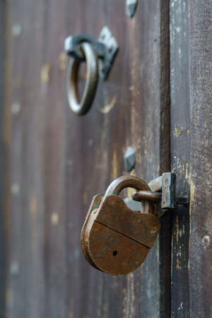 Detail of old padlock on wooden door and old knocker.の写真素材