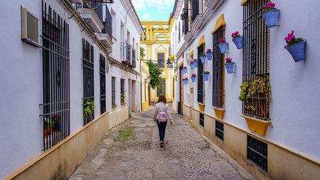 Woman walking through the narrow streets of Cordoba among plants and flowers in pots. Spain.の写真素材