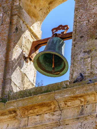 Bell in medieval stone church tower with blue sky.の写真素材
