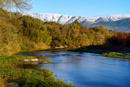 Sunny landscape with rays of sun, river with water and grass in winter sunrise. Gredos, Avila.