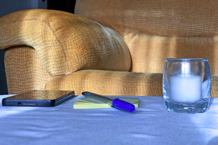 Taking notes at sunset next to the cell phone and a candleの写真素材